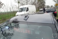 nieoznakowany radiowóz, przed nim funkcjonariusz kontroluje pojazd