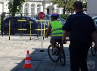 w obecności policjanta młodzież na rowerach korzysta z miasteczka ruchu drogowego