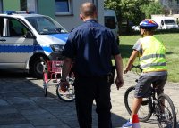 w obecności policjanta młodzież na rowerach korzysta z miasteczka ruchu drogowego