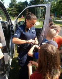 policjantka prezentuje dzieciom jak działają kajdanki