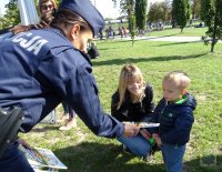 policjanta rozdaje dzieciom książeczki &quot;Bezpieczny Przedszkolak&quot;