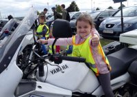 Zadowolona dziewczynka siedzi na policyjnym motocyklu.