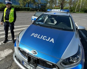 radiowóz, obok niego stojąca policjantka ruchu drogowego