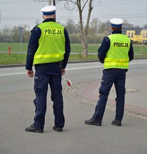 na zdjęciu dwóch policjantów stoi przy drodze