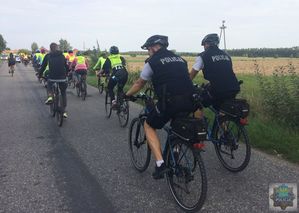 Policjanci drużyny rowerowej jadą na końcu kolumny uczestników rajdu rowerowego