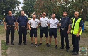 Siedmiu policjantów zabezpieczających rajd rowerowy pozuje do zdjęcia na boisku przy szkole w Kozłowicach.