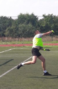 Piłkarz w stroju sportowym biega po boisku piłkarskim.