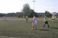 Młodzi mężczyźni biegają po boisku sportowym za piłką.
