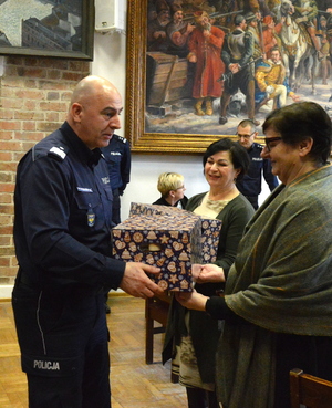 Komendant Wojewódzki Policji w Opolu przekazując prezent jednej z wdów po poległym policjancie
