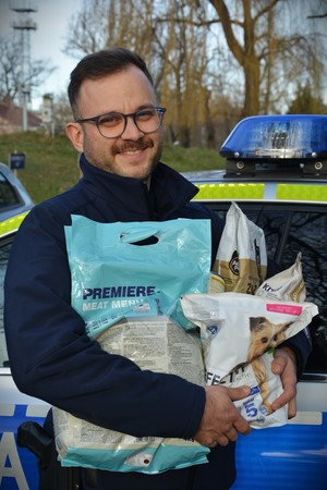 Policjant trzyma karmę dla zwierząt.