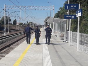 2 policjantów i 1 strażnik idą wzdłuż peronu