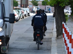 policjanci jadą jezdnią jeden za drugim na rowerach