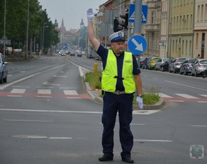 policjant ruchu drogowego stoi na środku skrzyżowania z uniesioną ręką