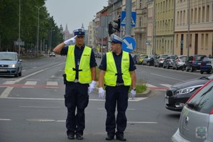 dwóch policjantów ruchu drogowego na środku skrzyżowania, jeden z nich salutuje