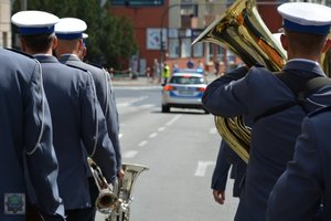 orkiestra policyjna idzie ulicą, w tle radiowóz