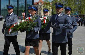 delegacja policjantów idzie z kwiatami pod tablicę pamiątkową