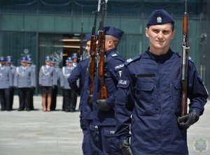 policjanci z Katowic podczas pokazu musztry paradnej: maszerują z bronią, kucają, podrzucają bronią, ich dowódca w dłoni trzyma szablę