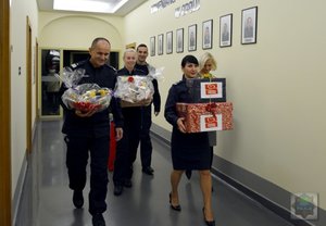 policjanci zaangażowani w akcję idą z prezentami przez korytaż