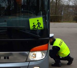 policjant kuca przy kontrolowanym autobusie