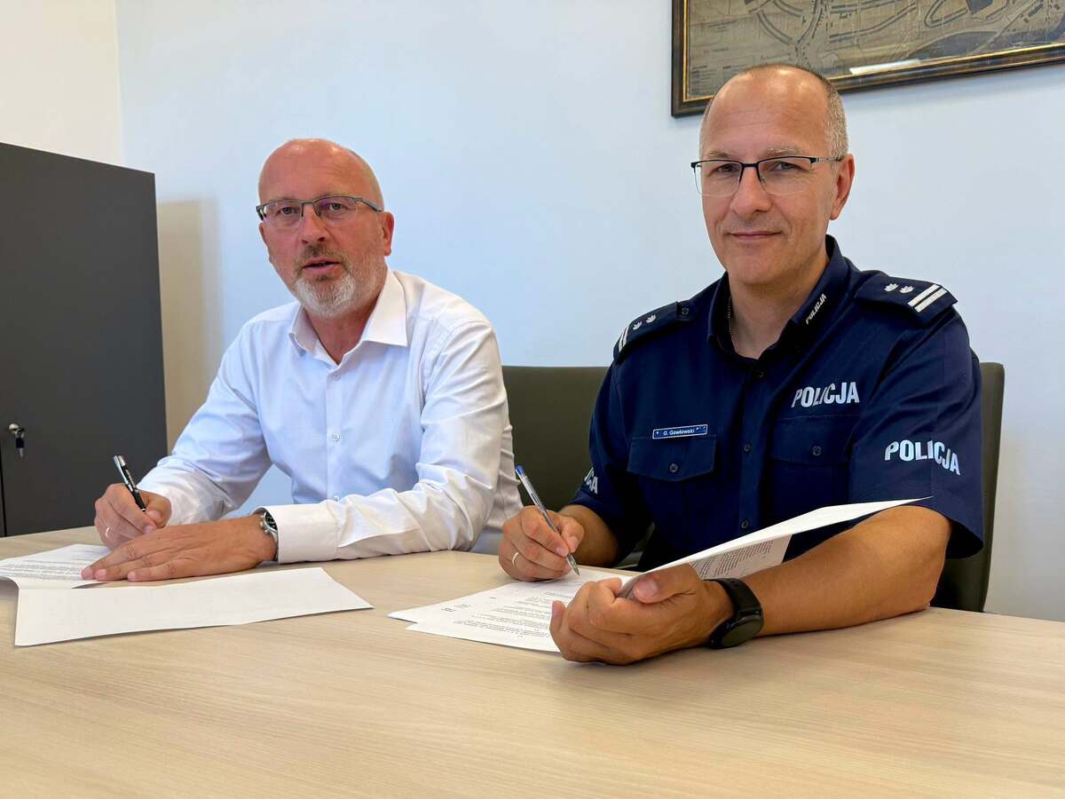 zdjęcie: Komendant Policji w Nysie oraz Burmistrz Głuchołaz siędzą przy tole i podpisują porozumienie 