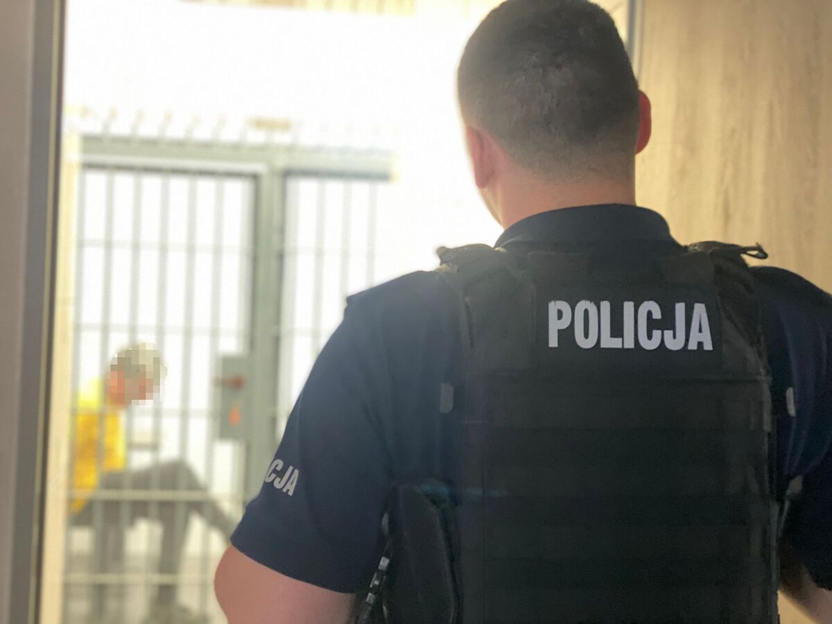 zdjęcie: policjant pilnujący osobą zatrzymaną 