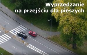 zrzut ekranu z drona, na którym widzimy jak jeden samochód wyprzedza inny na przejściu dla pieszych