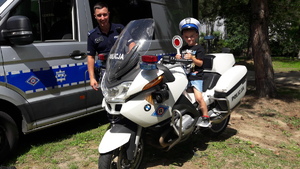 policjant, obok chłopiec na motocyklu policyjnym