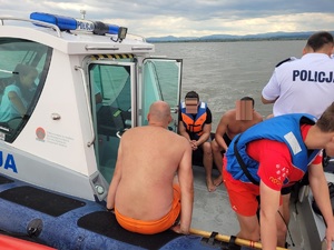 trzech mężczyzn, policjant i ratownik WOPR na policyjnej łodzi motorowej