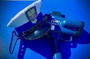 kolorowe zdjęcie - czapka policjanta ruchu drogowego oraz ręczny miernik prędkości