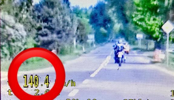 Zdjęcie kolorowe, na nim motocyklista oraz napis 140 w czerwonym kółku.