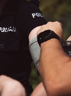 kolorowe zdjęcia na których widać funkcjonariuszy podczas szkolenia z zakresu pierwszej pomocy i korzystania ze staz taktycznych, tamowania krwotoków.