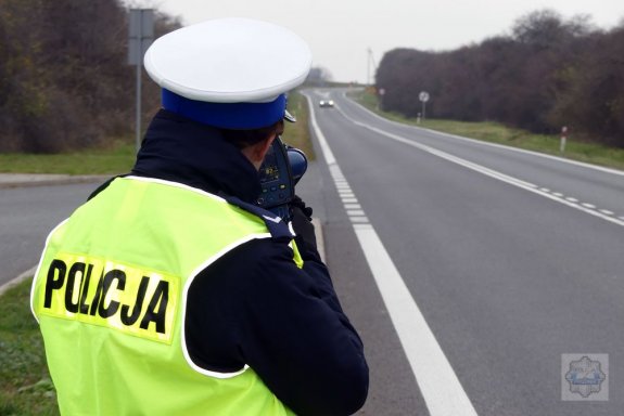 policjant z miernikiem prędkości stoi przy drodze