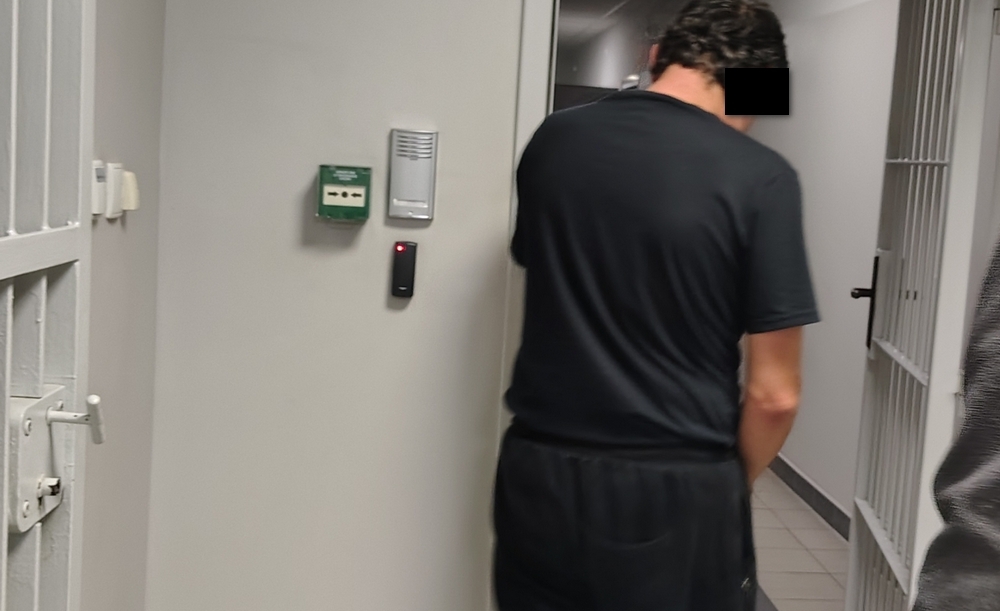 mężczyzna wchodzi do pomieszczenia dla zatrzymanych
