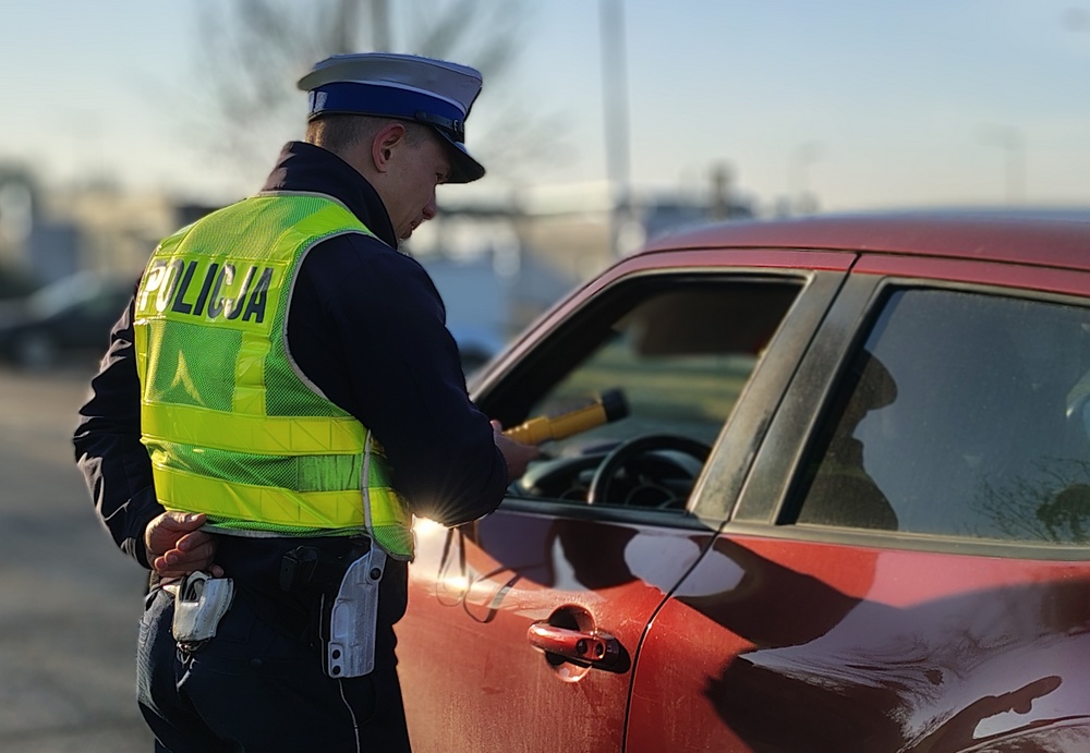 policjant z ruchu drogowego bada trzeźwośc kierowcy