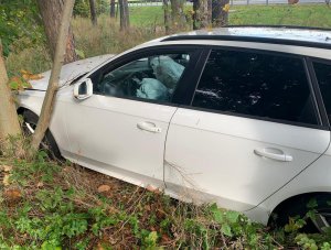 biały samochód osobowy combi uszkodzony po uderzeniu w drzewa