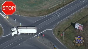 ujęcie z drona, na którym widać samochód ciężarowy na drodze,
znak STOP, logo opolskiej Policji