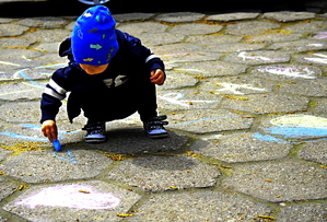 dzieci malujące kredą na płytach chodnikowych