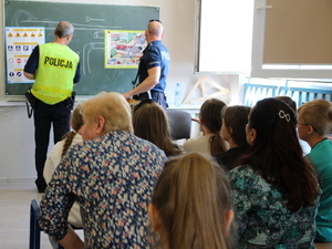 policjant w kamizelce odblaskowej podczas pogadanki z dziećmi w klasie