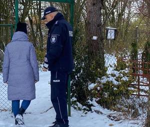 policjant i osoba cywilna wchodzą na zaśnieżone ogródki działkowe
