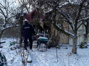 policjant sprawdza altankę na działce, otoczenie zaśnieżone