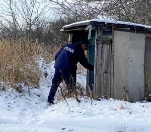 otoczenie zimowe policjant sprawdza altankę na ogródkach działkowych