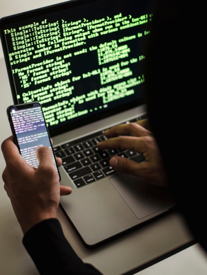 mężczyzna patrzy w telefon komórkowy i laptop