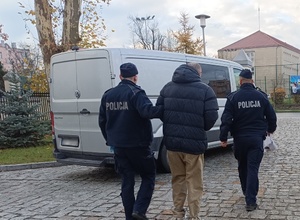 umundurowani policjanci prowadzą mężczyznę w kajdankach