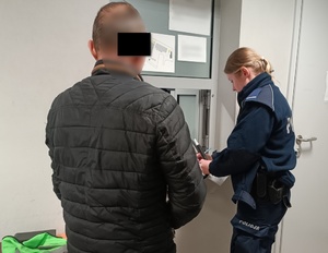 policjantka wypełnia dokumenty w obecności zatrzymanego