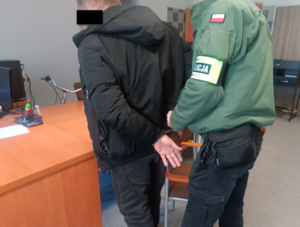 Policjant zapina kajdanki zatrzymanemu