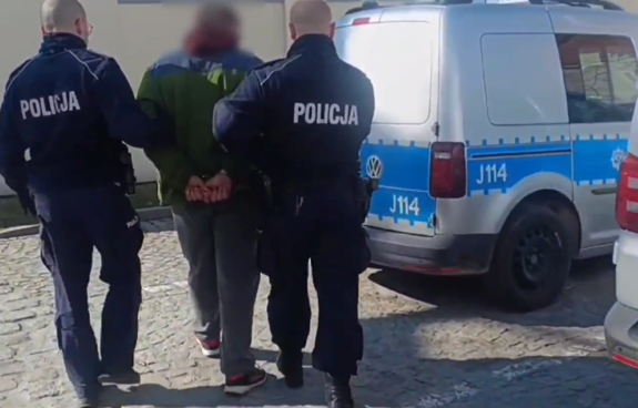 umundurowani policjanci prowadzą zatrzymanego mężczyznę
