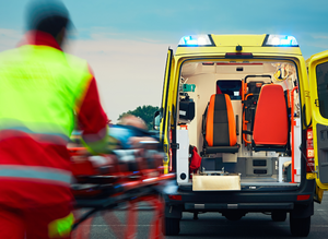 ratownik medyczny wiezie na noszach pacjenta do karetki pogotowia