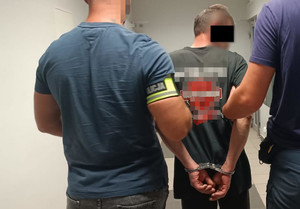 Policjanci prowadzą zatrzymanego
