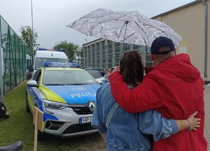 objęta para pod parasolem, w tle radiowóz