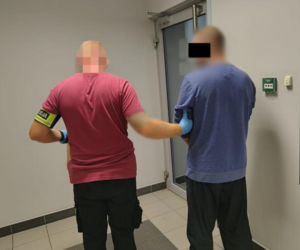 nieumundurowany funkcjonariusz prowadzi zatrzymanego